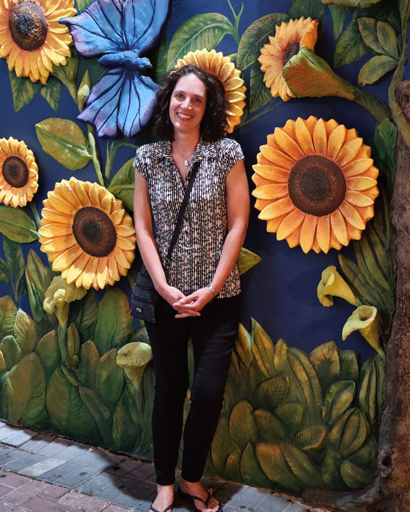 Travel Advisor Dawn Garvey standing in front of a wall painted with sunflowers in Curacao