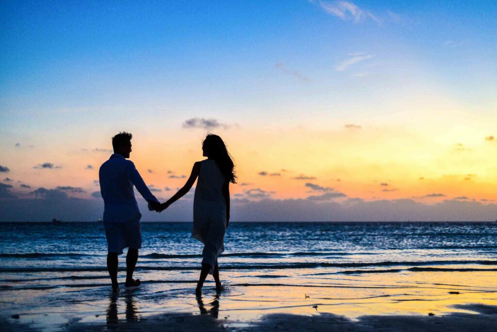 Romantic Cruise Blog A romantic couple walks hand in hand on a tropical beach at sunset, enjoying a serene moment together.