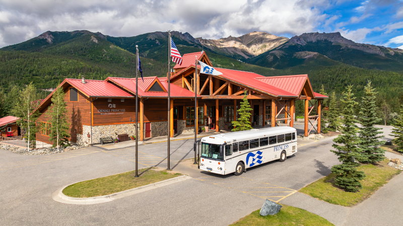 Princess Cruise Lines McKinley Lodge in Alaska with mountains in the background and a Princess Bus parked in front