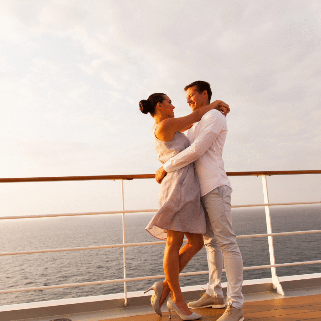 A man and a woman with their arms around each other standing on the deck of a cruise ship.